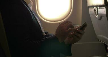 uomo utilizzando penna per genere su inteligente Telefono nel aereo video