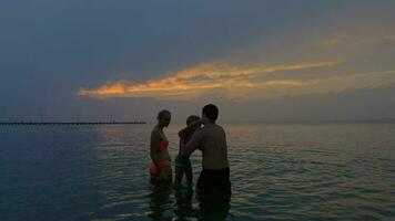 Family with child in the sea at twilight video