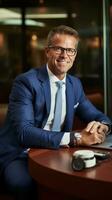 CEO sitting at desk with laptop and phone, wearing smartwatch photo