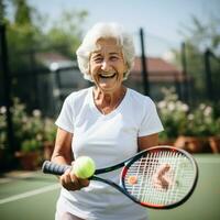 Elderly woman playing tennis with a smile on her face photo