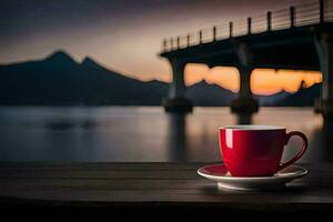 a red cup sits on a table in front of a bridge. AI-Generated photo