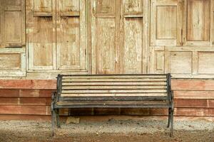 Closeup old long bench on wooden wall of house background. photo