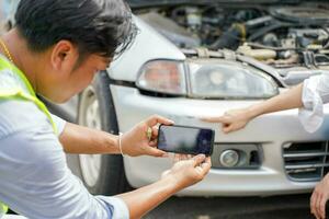 Closeup insurance company officers are using mobile phones to take photos as evidence for customer insurance car claims out door background.