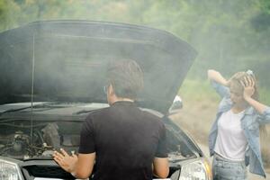 A male driver checks the condition of a car after an accident with an engine that smokes. photo