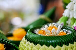 Closeup and crop banana leaves folded in a bowl and pot shape with ancient Thai desserts on blurred background. Thai desserts are unique in Thai national culture. photo