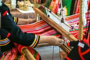 Closeup and crop hands of Thailander Hill tribe ladies are demonstration of weaving colorful fabric for tourists in her village. photo