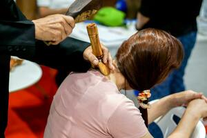 Closeup and crop Thai northern ancient medical use a wooden wedge and wooden hammer to poke around the body to heal body aches. photo