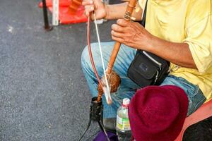 Closeup hands of Thai street musician playing Thai fiddle at Chiang mai walking street. The Thai fiddle is used in stringed instruments as the conductor and is the basis for the reference melody. photo