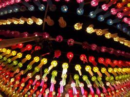 vista colorida hacia arriba y hacia abajo de las linternas de estilo lanna tailandés para colgar frente al templo en la noche en el festival de loy kratong. foto