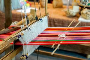 Closeup and crop colorful yarns with ancient wooden weaving machine on blurred background. photo