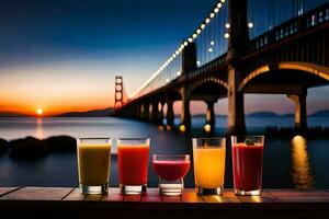 four glasses of juice are sitting on a table in front of a bridge. AI-Generated photo