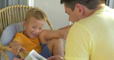 sorridente ragazzo ascoltando il suo padre lettura un' libro video