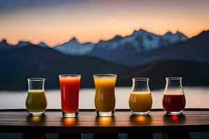 five glasses of juice on a table with mountains in the background. AI-Generated photo