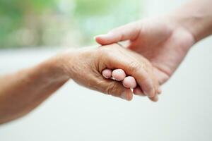 Asian young boy holding old grandmother woman hand together with love and care. photo