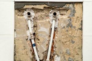 old plumbing with metal-plastic pipes in wall photo