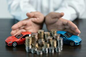 Close-up Of A Person's Hand Protecting Increasing Stacked Coins And Blue Car. Saving money for car concept, trade car for cash concept, finance concept. photo