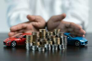 Close-up Of A Person's Hand Protecting Increasing Stacked Coins And Blue Car. Saving money for car concept, trade car for cash concept, finance concept. photo