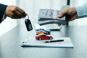 Closeup hand giving a car key and money for loan credit financial, lease and rental concept photo