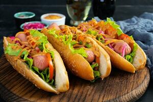 Hot dog with lettuce, tomatoes and pickled onions. Grilled bun with sausage photo