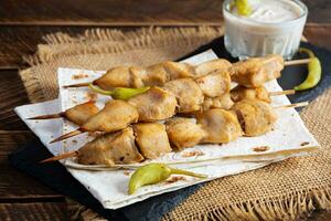 Chicken kebab with sour cream sauce. Chicken skewers on wooden background photo