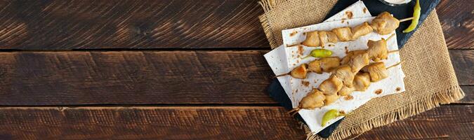 Chicken kebab with sour cream sauce. Chicken skewers on wooden background photo