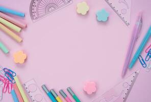 School stationery lie in the shape of a frame on pink background. Back to school. Flatlay composition. Top view. Copy space. photo