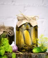 Canned cucumbers in a jar, garlic, dill and spices on a natural wooden background. Close-up. photo