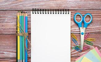 Back to school. Blank notepad and school stationery on a wooden background. Flatlay composition. Mockup. Top view. Copy space. photo