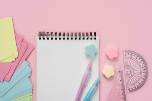 Blank notepad and school stationery on a pink background. Back to school. Flatlay. Mockup. Top view. Place for text. photo