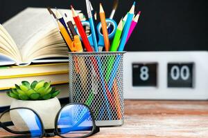 Back to school. Bright stationery, books, glasses and watches on a wooden desk. Close-up. Selective focus. photo