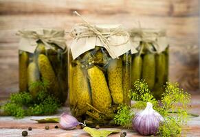 Homemade preserved cucumbers in jars on a wooden background. Rustic style. Delicious homemade pickled. Close-up. photo