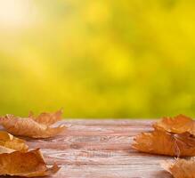 de madera mesa con otoño arce hojas y borroso otoño antecedentes. Copiar espacio. selectivo enfocar. foto