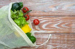 Fresh vegetables and fruits in eco bag on a wooden background. Zero waste concept. Copy space. Selective focus. photo