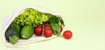 Eco bag with fresh vegetables on a green background. Zero waste concept. Copy space. Selective focus. photo