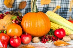 On a wooden table pumpkins, various vegetables and autumn leaves. Autumn mood. Happy Thanksgiving. Close-up. photo