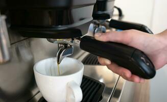 The coffee machine pours coffee into a cup. The barista brews natural coffee. Close-up. Selective focus. photo