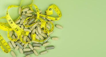 Fitness, sport and healthy lifestyle concept. Natural vitamins and supplements on a green background. Top view. Copy space. Selective focus. photo