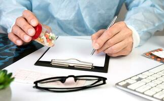 Close-up of the hands of a male doctor writing a prescription to a patient in a clinic. The concept of healthcare and medicine. photo