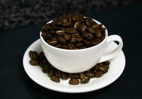 Natural coffee beans in a white cup on the table. Coffee day. Close-up. Selective focus. photo