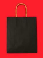 Paper black shopping bag mockup on the red background. Copy space. photo