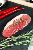 Raw organic beef meat with rosemary, seasonings, salt and red pepper  on black background photo