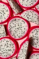 Slices of fresh white pitaya or dragon fruit on pink background, flat lay photo