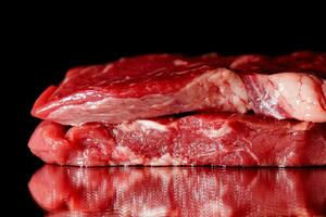 Raw organic beef meat with rosemary, seasonings, salt and red pepper  on black background photo