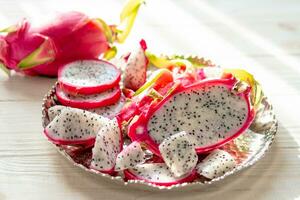 Slices of fresh white pitaya or dragon fruit on wooden background, top view photo