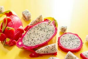 Slices of fresh white pitaya or dragon fruit on yellow background, flat lay photo