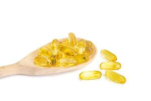 Pile of capsules Omega 3 in wooden spoon isolated on white background photo