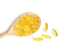 Pile of capsules Omega 3 in wooden spoon isolated on white background photo