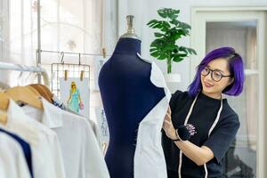 Fashionable freelance dressmaker is pinning her marking muslin for new dress by pinning to mannequin while working in her artistic workshop studio for fashion design and clothing business industry photo