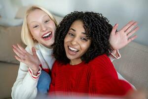 Shot of a two female friends taking selfie in the apartment. My roomies. Shot of two young women taking a selfie while sitting at home. Shared Living roommates make a selfie photo