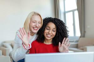 Two beautiful women using laptop for an online video call and online toasting with their friends. Online party for friends. photo